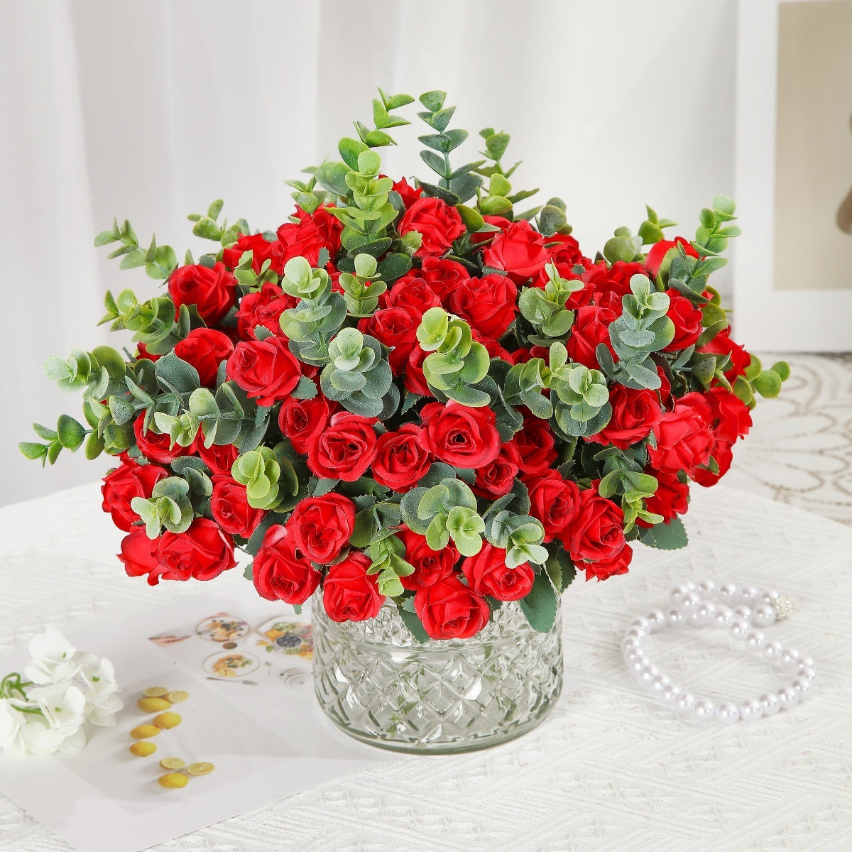 Red silk rose bouquet with green eucalyptus in crystal vase for living room decoration or wedding ceremony artificial flower arrangement.